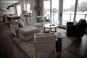 Een moderne woonkamer met een hoekbank, een ronde salontafel en een bijzettafeltje.