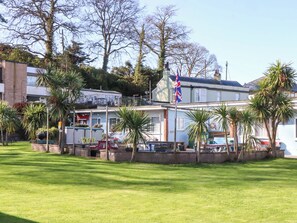 A building with a flag, surrounded by palm trees and a grassy area. - Sea Glimpse (Dawlish)