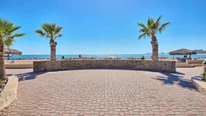 Un espace aménagé avec des palmiers, un mur en pierre et une vue sur la mer.