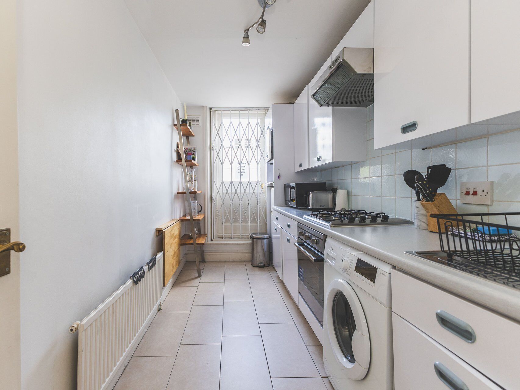 Une petite cuisine équipée d’un lave-linge, d’une cuisinière et d’un four à micro-ondes.