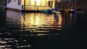 Una casa flotante con terraza techada y un pequeño bote amarrado cerca.