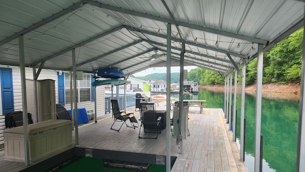 Una terraza techada con piscina, asientos exteriores y vista al río.