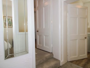 A hallway with white doors, a mirror, and a carpeted staircase. - The Apartment at the Grey House (Wolverhampton)
