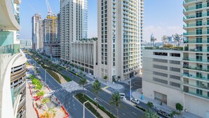 A modern high-rise building with multiple balconies, a pedestrian walkway, and a clear sky. - Stylish 1BR with Private Beach Access (Dubai)