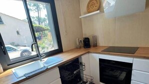 Una cocina moderna con lavavajillas, horno y ventana con vistas a una zona residencial.