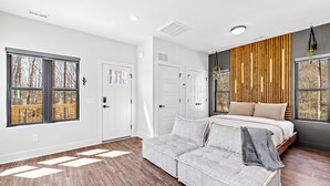 Un dormitorio con una cama, un sofá gris y una pared de acento de madera.