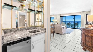 A modern kitchen with granite countertops, a dishwasher, and a dining area with a balcony overlooking the sea. - Emerald Towers 0605 - Gulf-front condo with private balcony and beach access in Destin (Destin)