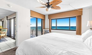 Ein Hotelzimmer mit einem großen Bett, einem Deckenventilator, Blick aufs Meer und einem Balkon.
