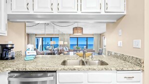 A modern kitchen with granite countertops, a stainless steel sink, and white cabinetry. - Emerald Towers 0605 - Gulf-front condo with private balcony and beach access in Destin (Destin)