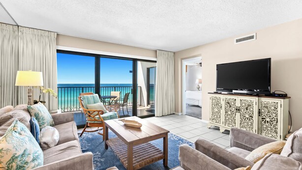 A hotel room with a balcony, a television, and a dining area. - Emerald Towers 0605 - Gulf-front condo with private balcony and beach access in Destin (Destin)