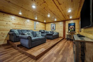 Ein gemütliches Zimmer mit Holzwänden und Holzdielen, ausgestattet mit einer Sofagarnitur, einem kleinen Tisch und einer Bar.
