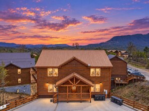 Eine Holzhütte mit einer auffälligen Veranda, einer Garage und Blick auf die umliegende Landschaft.