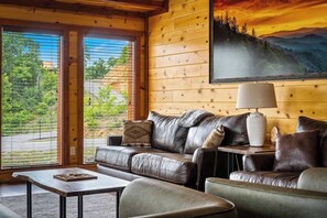 A cozy room with a leather sofa, a small table, and a lamp. - 6-Bedroom Cabin with Indoor Pool, Home Theater & Game Room Near Dollywood (Sevierville)