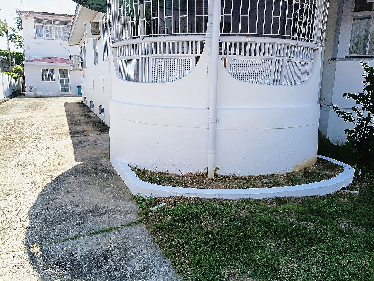 Una estructura cilíndrica con exterior blanco, posiblemente un depósito de agua, junto a un edificio con balcón.