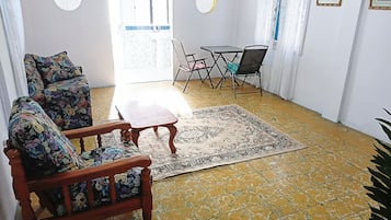 Una sala de estar con un sofá de madera, una mesita pequeña y un tapete estampado.