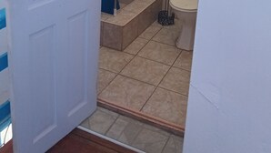 Une salle de bain avec des toilettes, un rideau de douche et un carrelage au sol.