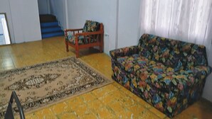 A living room with a sofa, a patterned rug, and a staircase in the background.