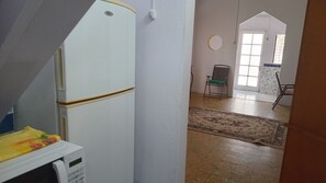 Keittiö, jossa on jääkaappi, mikroaaltouuni ja ruokapöytä tuoleineen.