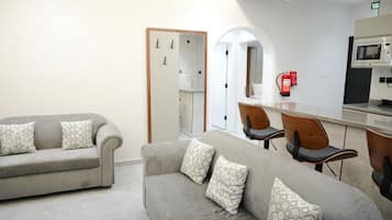 Habitación de hotel con sofá, sillas, microondas y extintor.