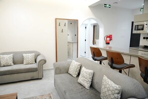 A hotel room with a sofa, chairs, a microwave, and a fire extinguisher. - Al Jawhara Suite Holiday Homes (Taif, Saudi Arabia)