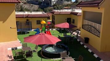 An outdoor patio area with seating, a water feature, and a view of the surrounding landscape.
