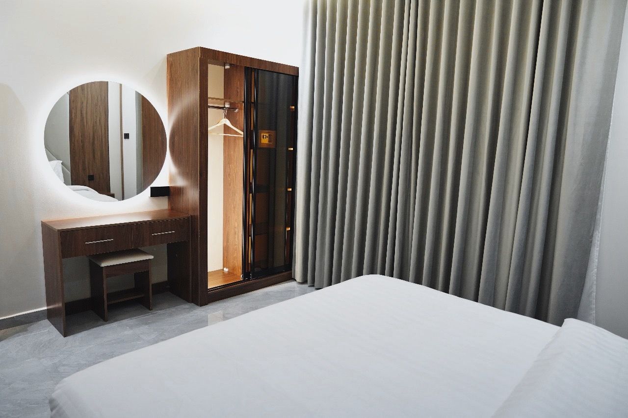 Ein Hotelzimmer mit einem Bett, einem Holzschrank, einem Spiegel und einem Vorhang.