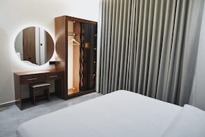 Ein Hotelzimmer mit einem Bett, einem Holzschrank, einem Spiegel und einem Vorhang.