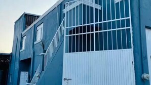 A multi-story building with a blue exterior, white railings, and a gated entrance.