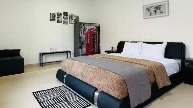 A modern bedroom with a bed, a small table, a bench, and a world map on the wall.