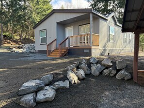 A single-story cabin with a wooden staircase, a front porch, and a gravel driveway. - Boyd Road Base Camp - Gateway to the Mountains (Randle)