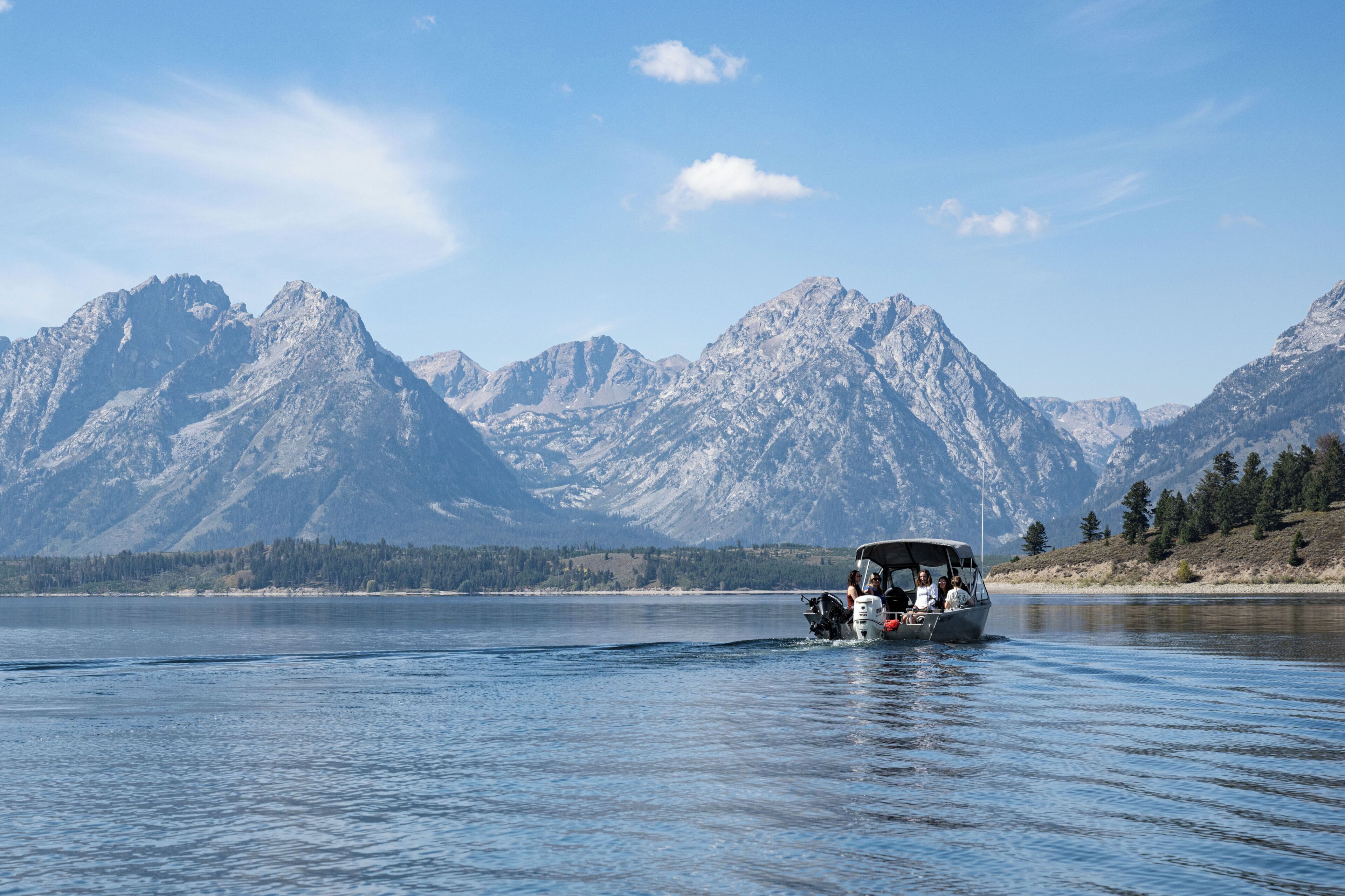 A boat on a calm lake with mountains in the background.