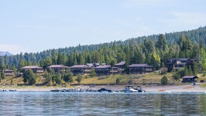 A lakeside resort with multiple buildings, boats, and a forested hillside.