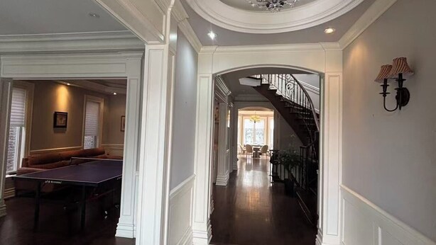 Un vaste hall d’entrée avec un sol en marbre, une table de billard et un escalier menant à un deuxième étage.