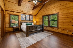 A wooden cabin bedroom with a bed, a nightstand, a lamp, and a world map on the wall. - Luxe Cabin w/ Pool, Game Room, Hottub - Sleeps 26 (Sevierville)