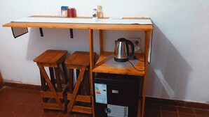 Une petite cuisine équipée d’une table en bois, de deux tabourets, d’une machine à café et d’un réfrigérateur.