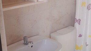 Une salle de bain avec un meuble-lavabo en bois, un évier, des toilettes et un rideau de douche orné de motifs de papillons.