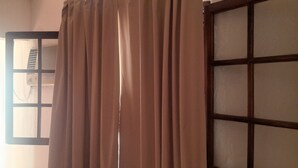 Une pièce avec une fenêtre, des rideaux et un climatiseur fixé au mur.