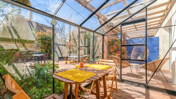 Un porche acristalado con muebles de madera y vista al jardín.