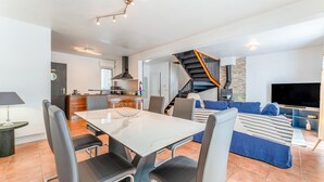 Un espacio habitable moderno con comedor, cocina y una escalera que lleva a un nivel superior.
