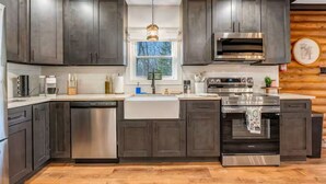 Una cucina moderna con mobili scuri, elettrodomestici in acciaio inossidabile e una finestra vista alberi.