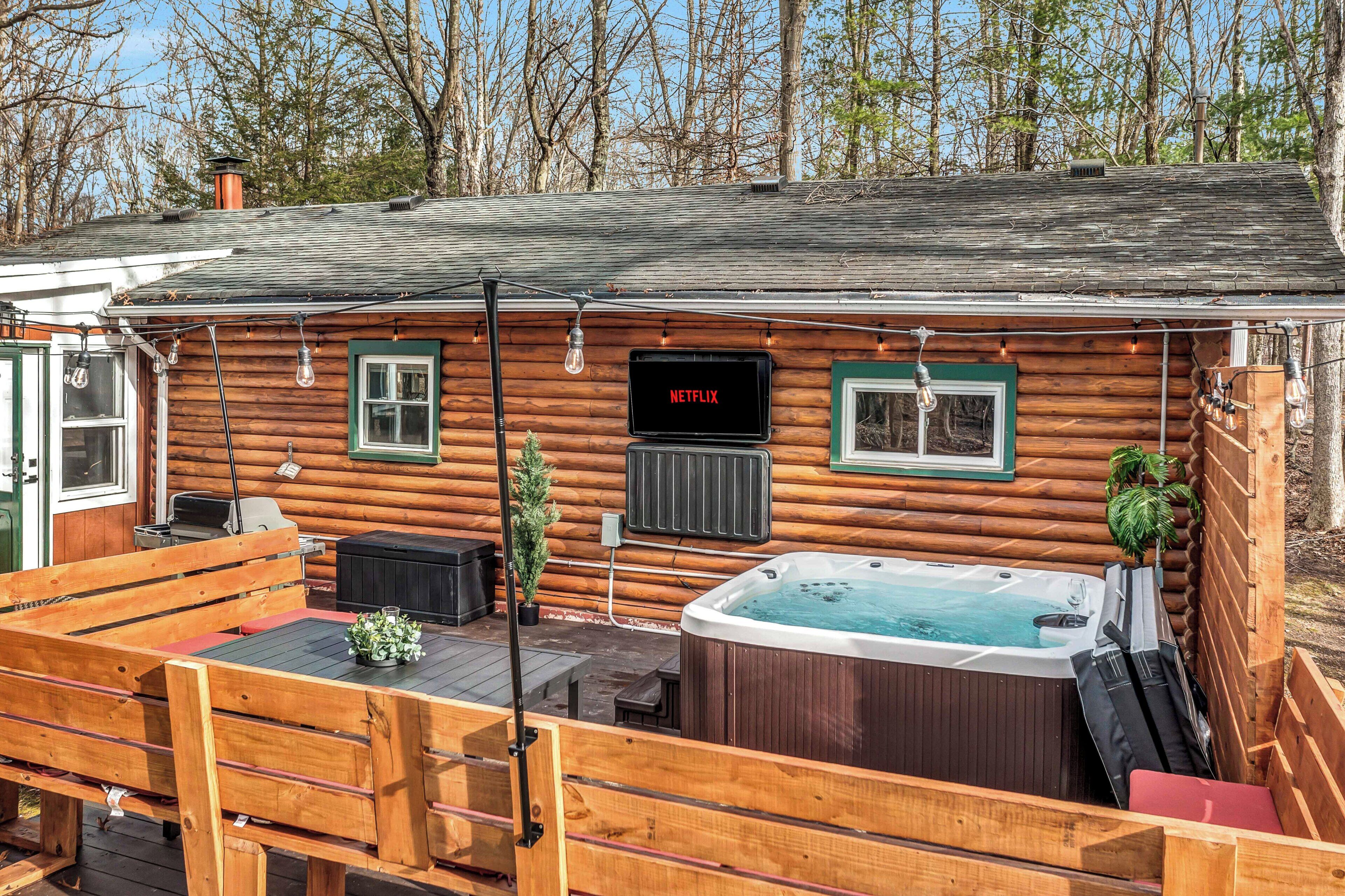 A log cabin with a hot tub, outdoor seating, and a Netflix sign.