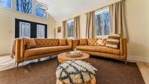 Ein Wohnzimmer mit einem großen Ecksofa, einem runden Couchtisch und einem flauschigen Teppich.