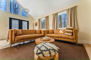 Ein Wohnzimmer mit einem großen Ecksofa, einem runden Couchtisch und einem flauschigen Teppich.