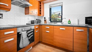 Eine moderne Küche mit Holzausstattung, einer Edelstahl-Dunstabzugshaube und einem Fenster mit Blick.