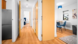 Ein Korridor mit Holzboden, weißen Wänden und einem Küchenbereich mit einem Kühlschrank.