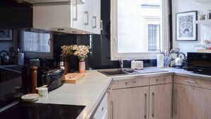 Une cuisine moderne dotée d’une grande fenêtre, de meubles en bois et d’une hotte de cuisine en acier inoxydable.