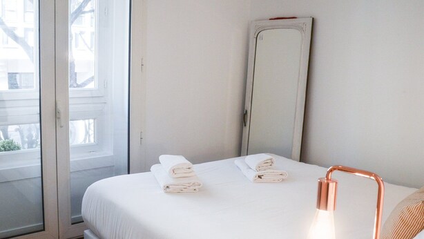 Une chambre d’hôtel avec un lit, un grand miroir et une fenêtre.