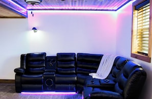 A black leather reclining sofa with a remote control, a speaker, and a blanket.