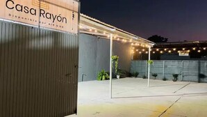 A building with a sign reading 'Casa Rayón' and a covered outdoor area with string lights.