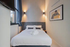 A hotel room with a bed, two wall-mounted lights, a framed picture, and a window with curtains. - Hotel ARENA byAstiblanco (Valencia)